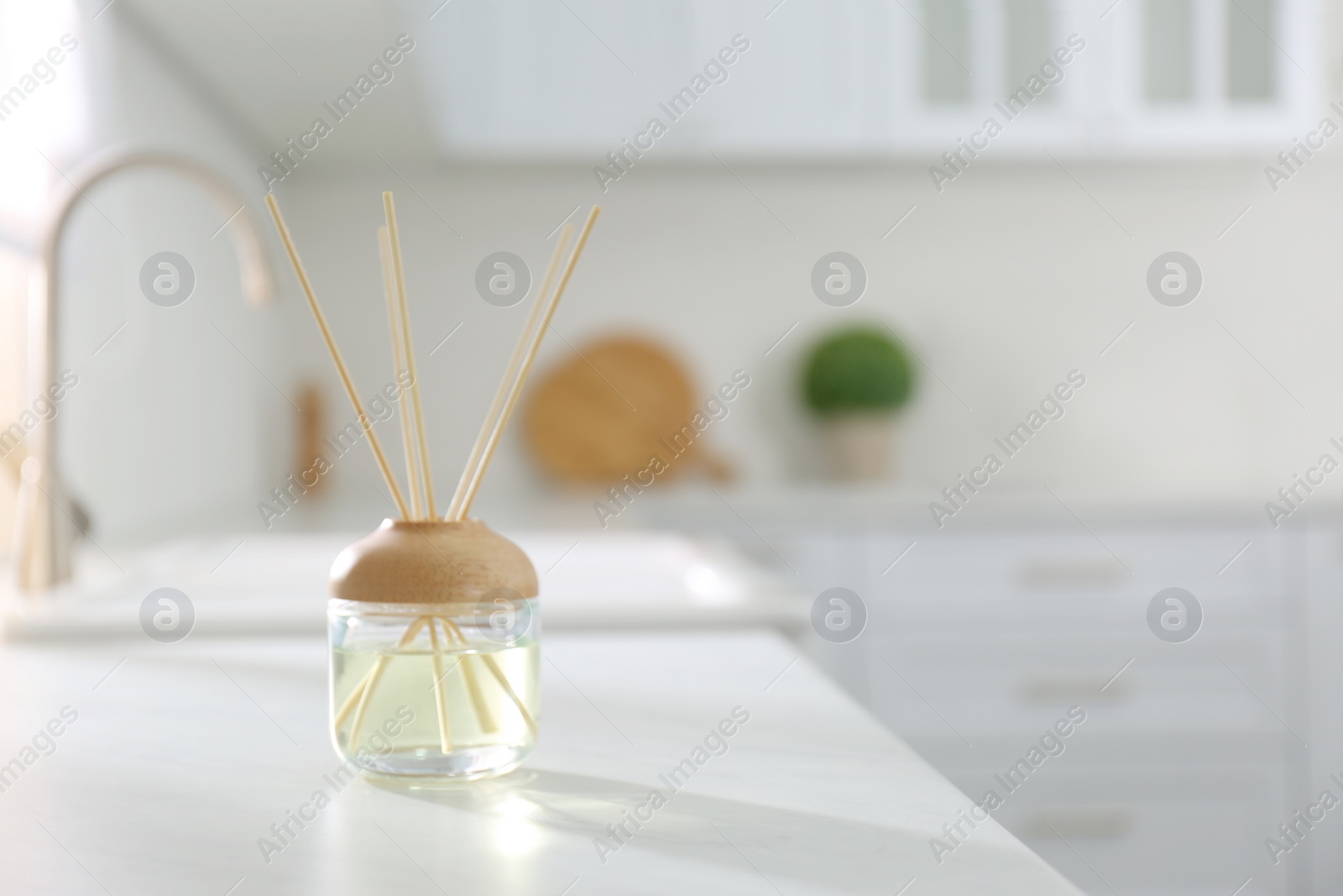 Photo of Aromatic reed air freshener on white table indoors. Space for text