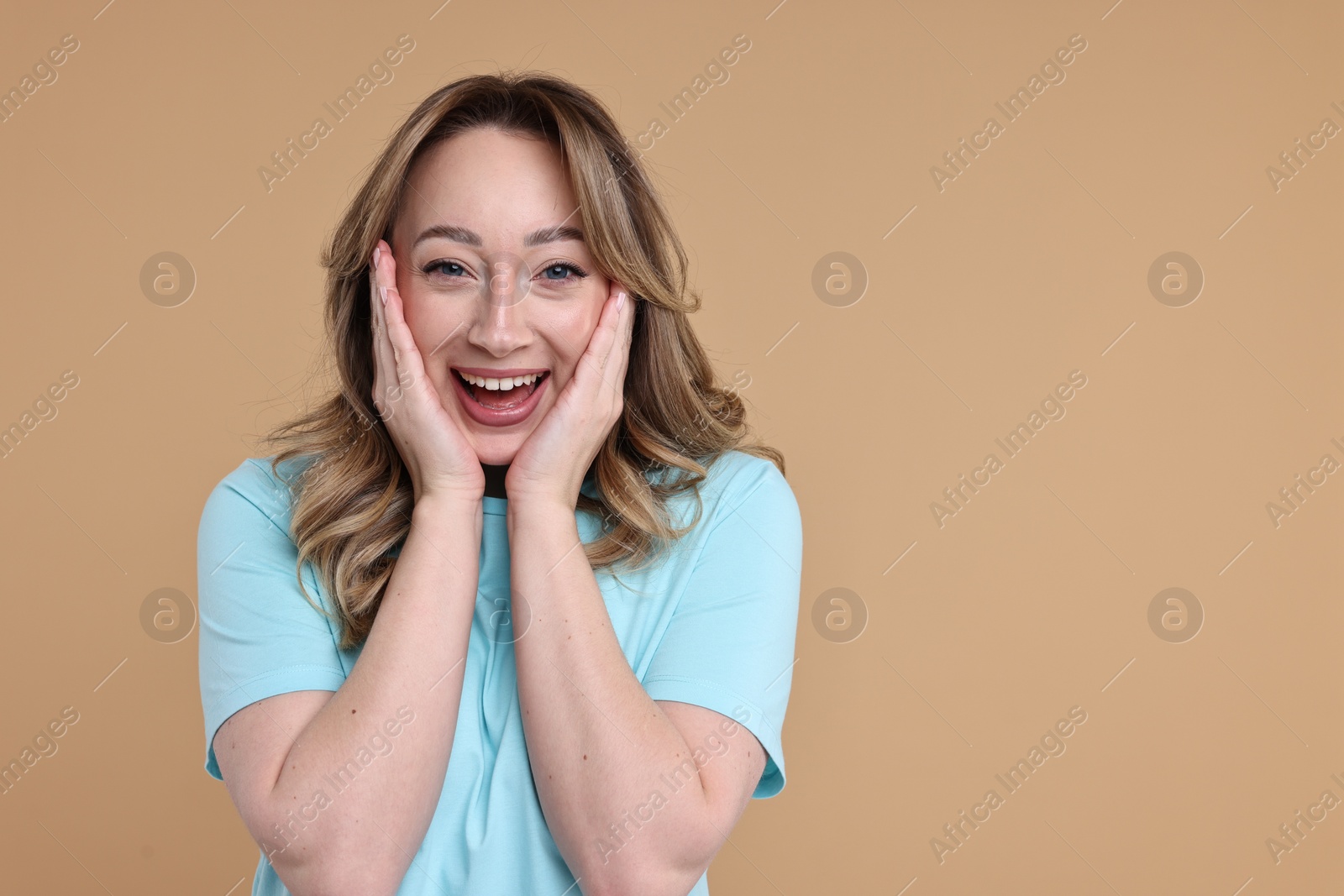 Photo of Portrait of happy surprised woman on beige background. Space for text