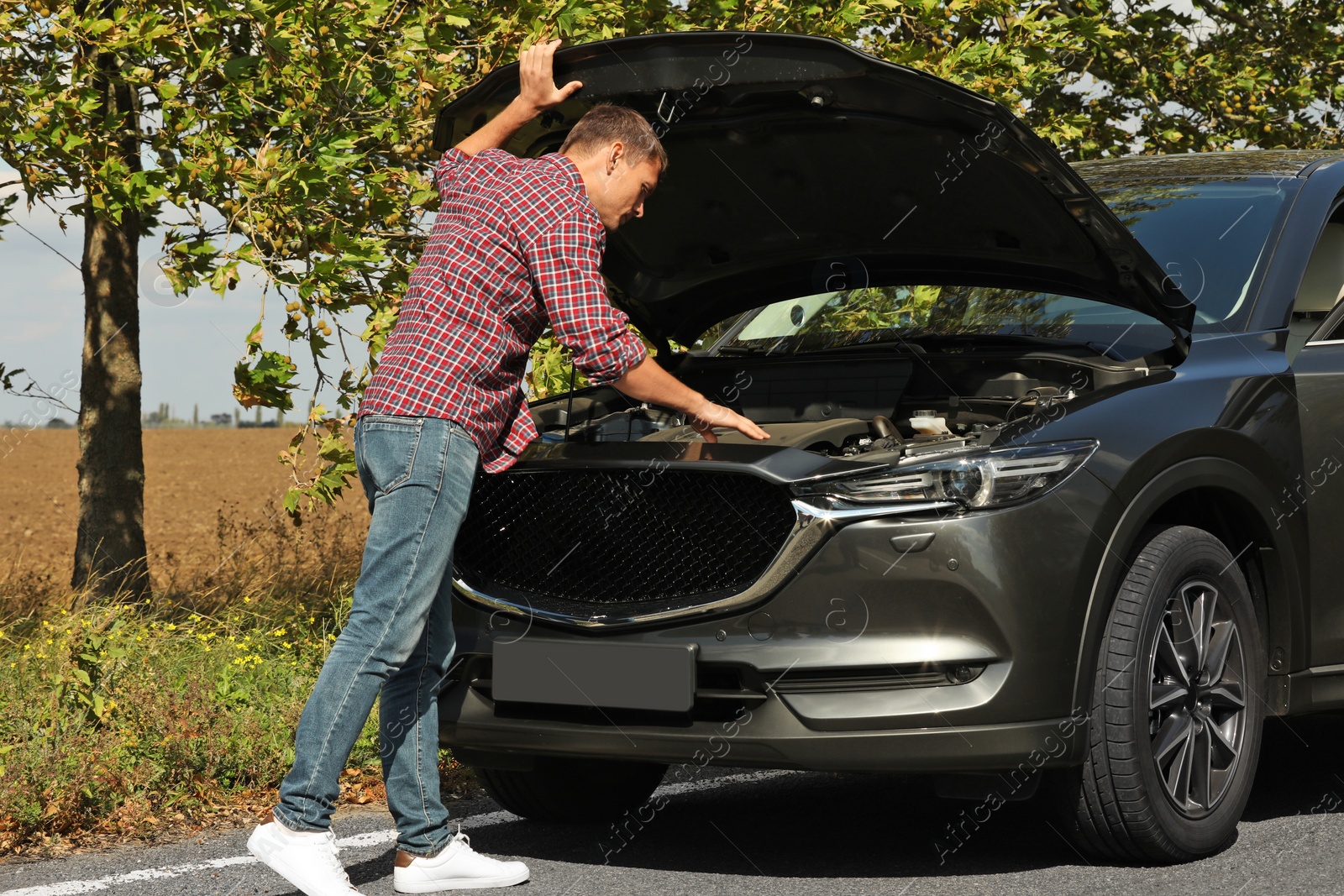 Photo of Man near broken car on road. Auto insurance