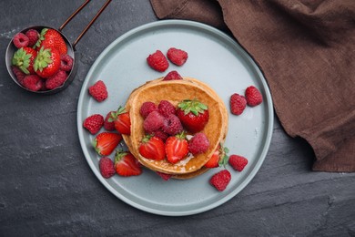 Photo of Tasty pancakes served with honey and berries on black table, flat lay