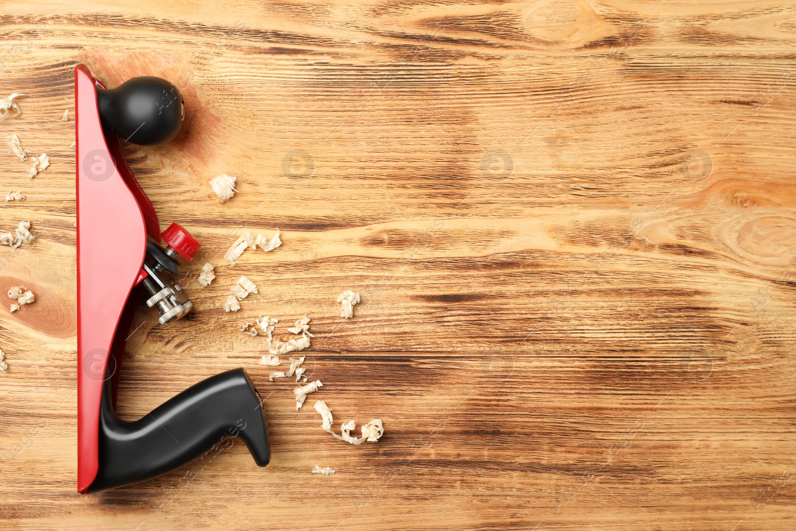 Photo of Modern jack plane and shavings on wooden background, top view with space for text. Carpenter's tool