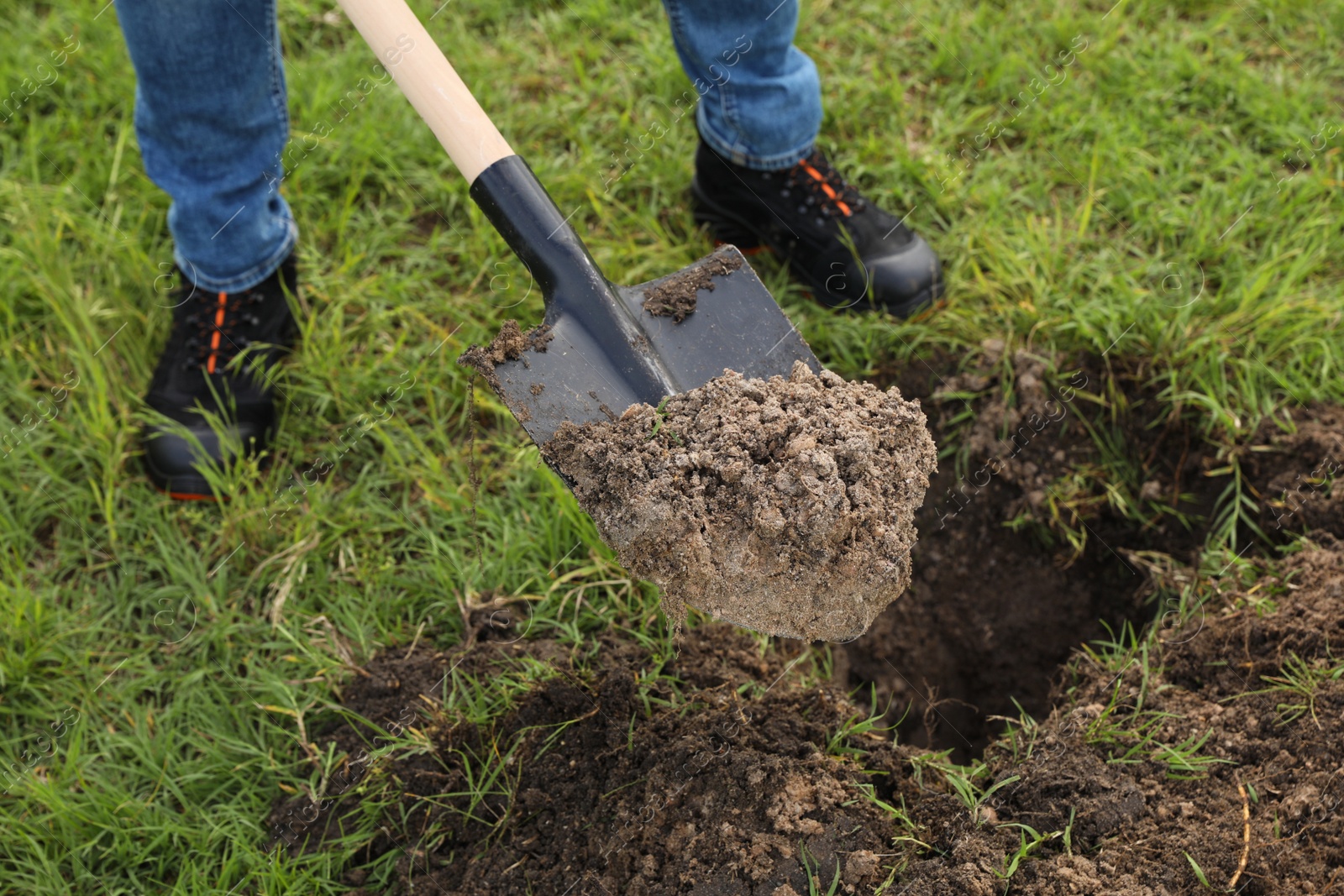 Photo of Worker digging soil with shovel outdoors, closeup