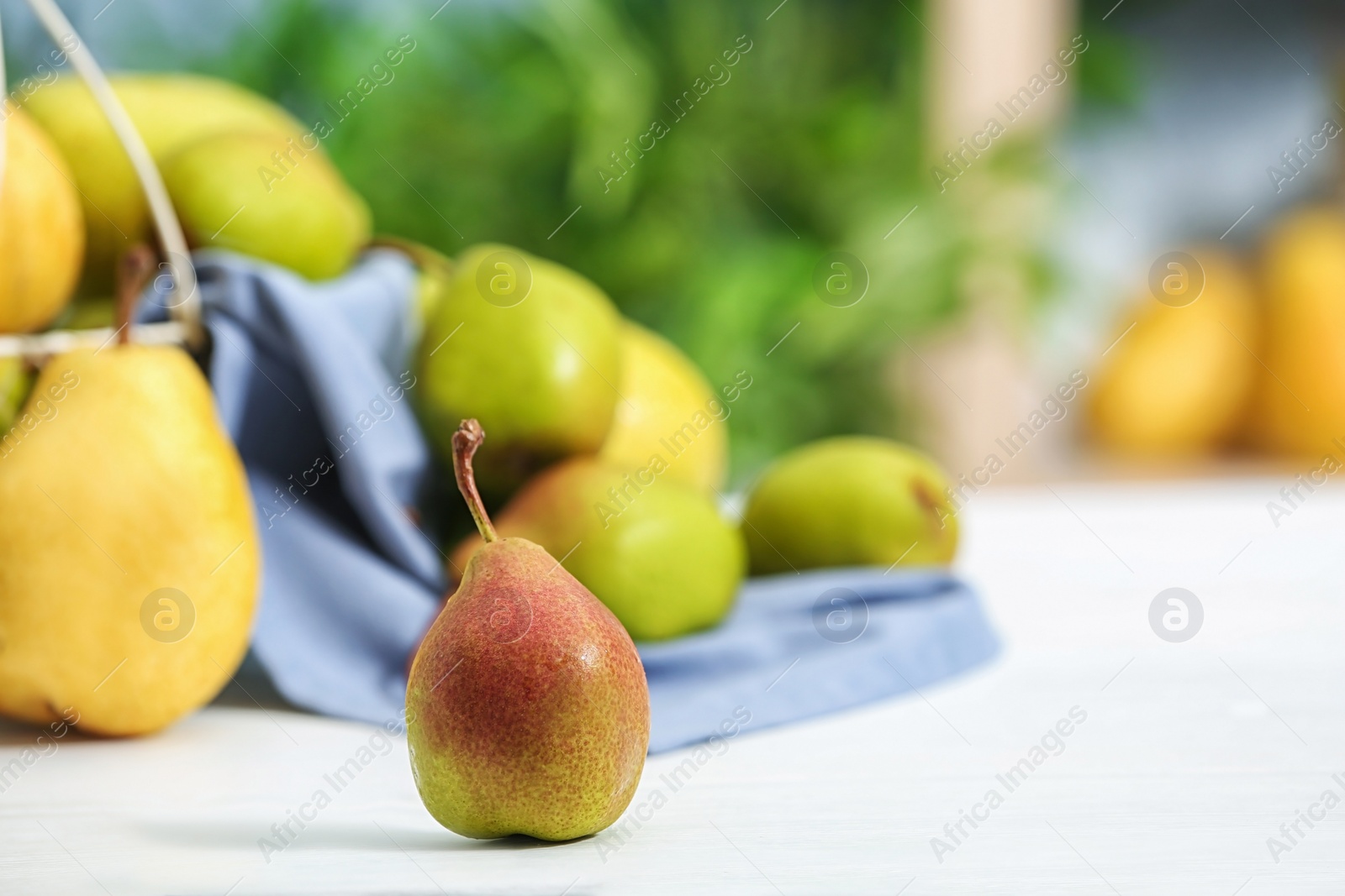 Photo of Fresh ripe pear on light table against blurred background