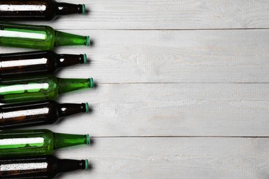 Glass bottles of beer on grey wooden background, flat lay. Space for text
