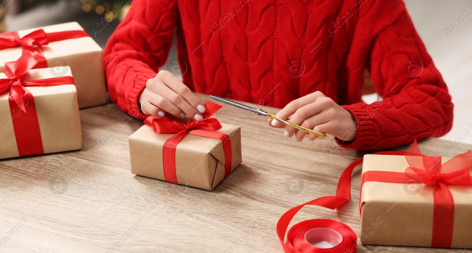 Photo of Woman decorating Christmas gift box at wooden table indoors, closeup