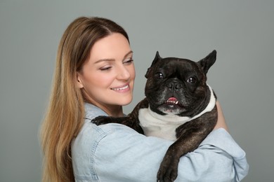 Photo of Happy woman hugging cute French Bulldog on grey background