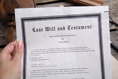 Woman holding last will and testament at table, closeup