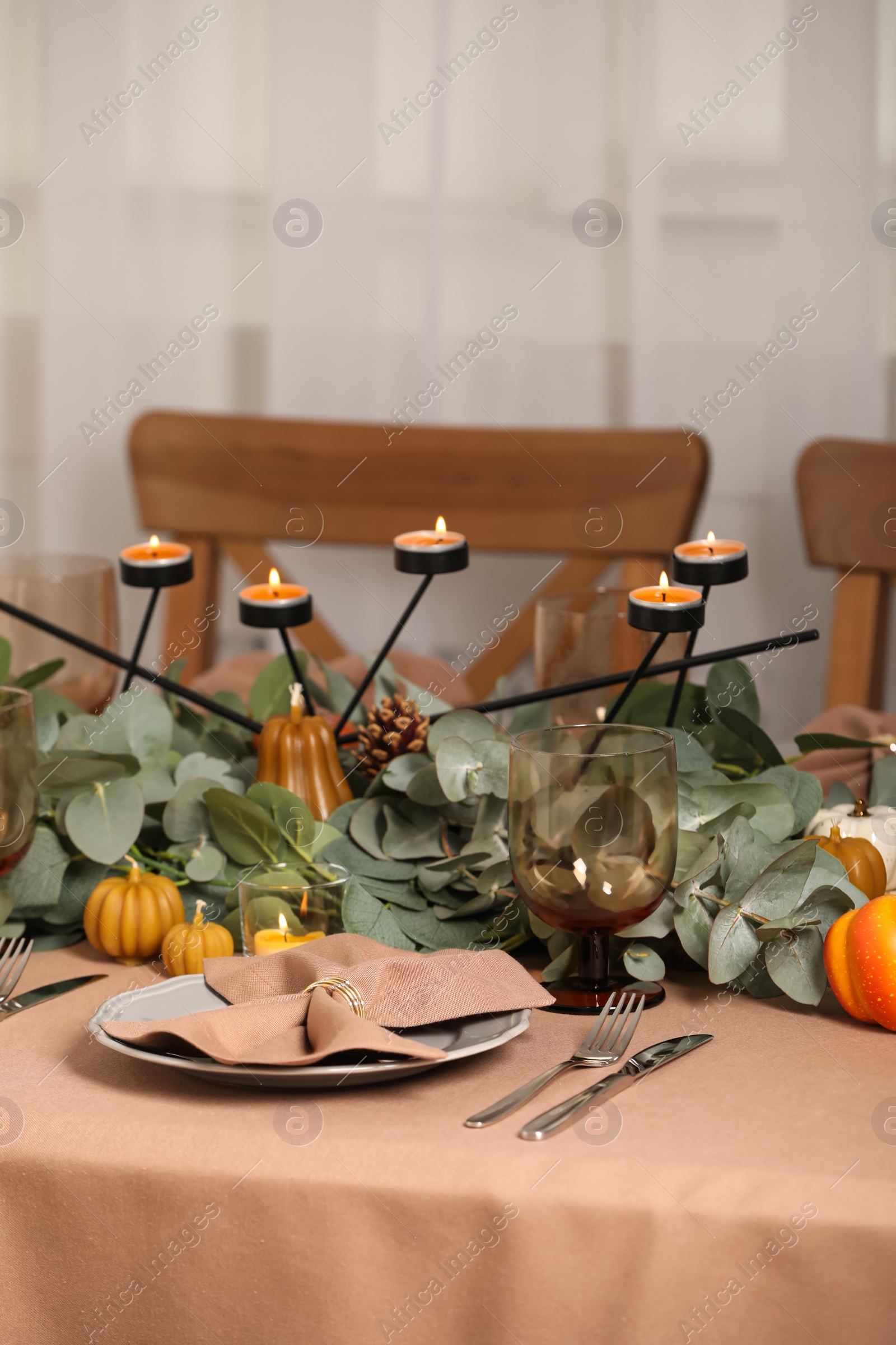 Photo of Autumn table setting with eucalyptus branches and pumpkins indoors