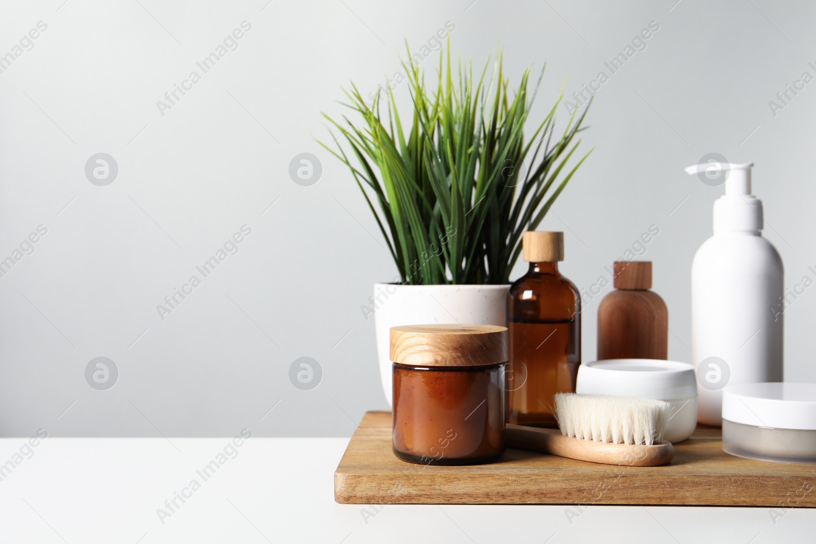 Photo of Different bath accessories and houseplant on white table against grey background. Space for text
