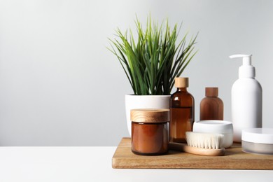 Different bath accessories and houseplant on white table against grey background. Space for text