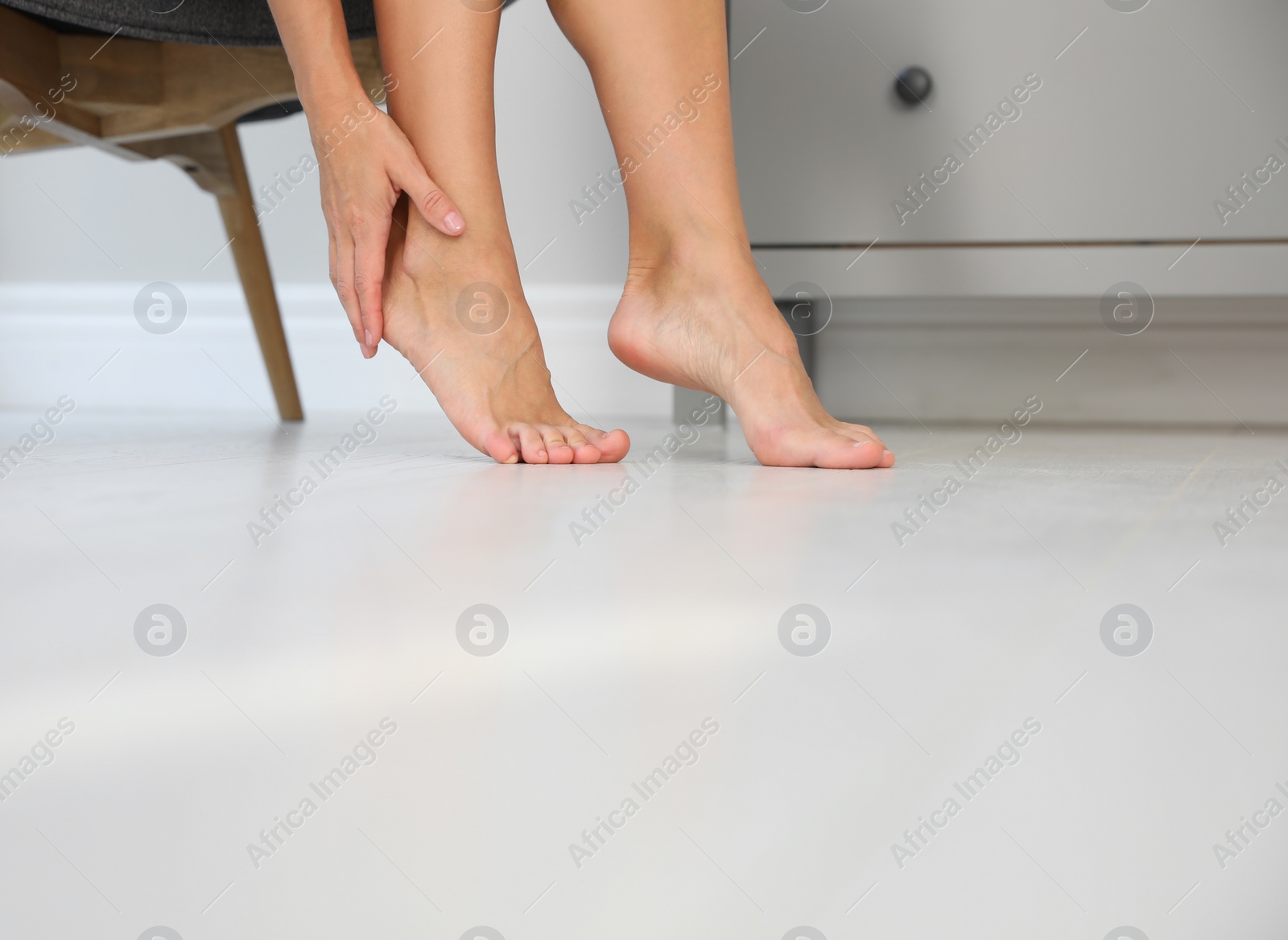Photo of Woman suffering from foot pain at home, closeup