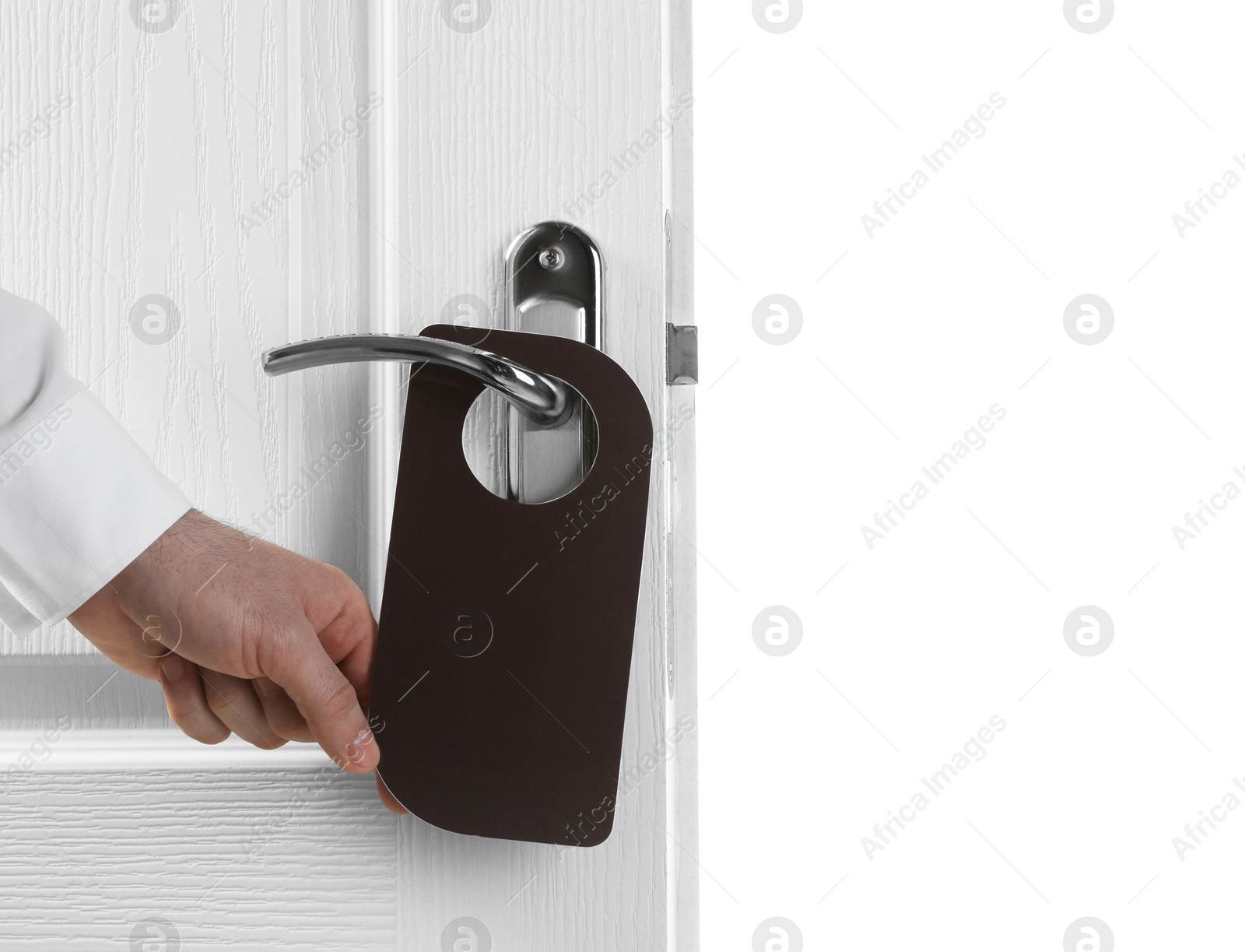 Photo of Man putting blank hanger on hotel door handle against white background, closeup