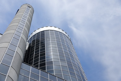 Modern building with tinted windows against sky, low angle view. Urban architecture