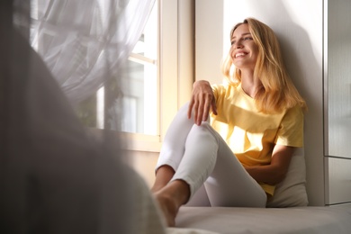 Photo of Beautiful young woman relaxing near window at home