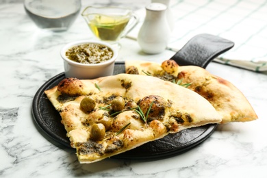 Photo of Delicious focaccia bread with green olives on white marble table