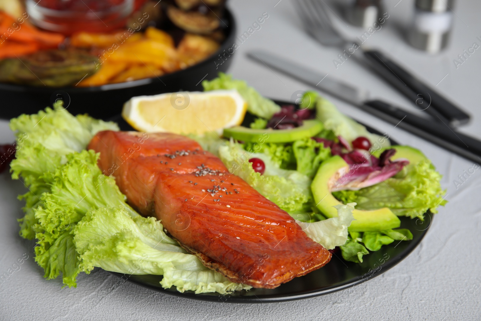 Photo of Tasty cooked salmon and fresh salad served on grey table. Healthy meals from air fryer