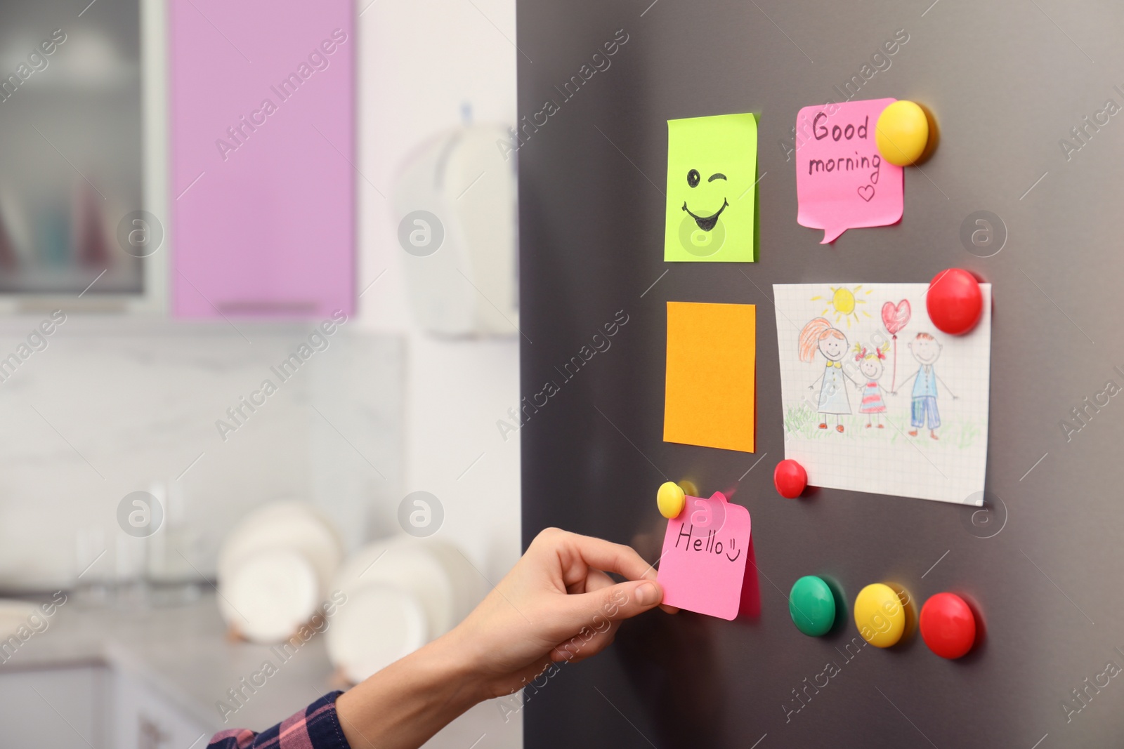 Photo of Woman putting paper note on refrigerator door at home, closeup