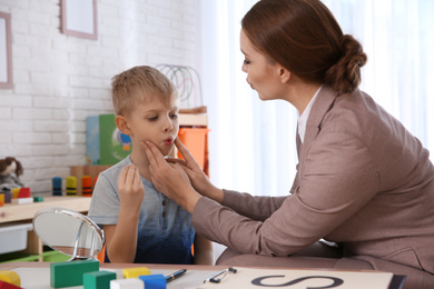 Speech therapist working with little boy in office