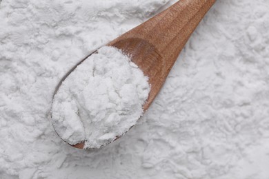 Photo of Heap of natural starch and wooden spoon, top view