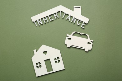 Word Inheritance, car and house models on green background, flat lay