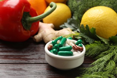 Photo of Dietary supplements. Pills in bowl and food products on wooden table