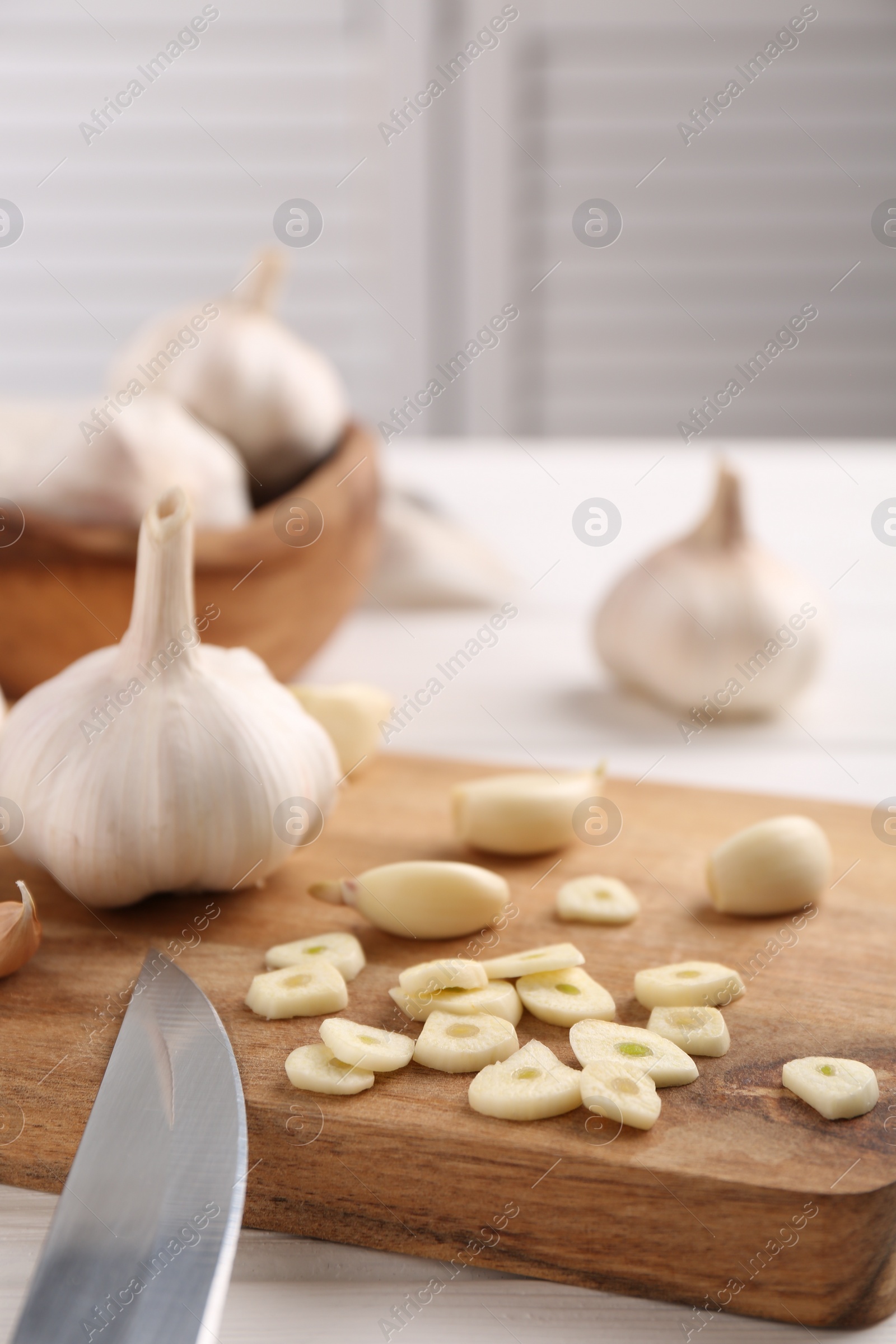 Photo of Aromatic cut garlic, cloves and bulbs on white wooden table, closeup