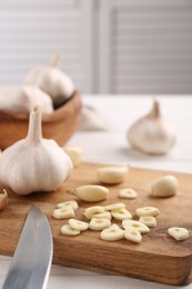 Photo of Aromatic cut garlic, cloves and bulbs on white wooden table, closeup