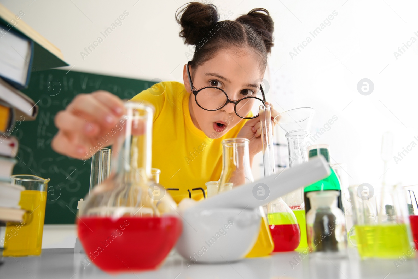 Photo of Schoolchild making experiment at table in chemistry class