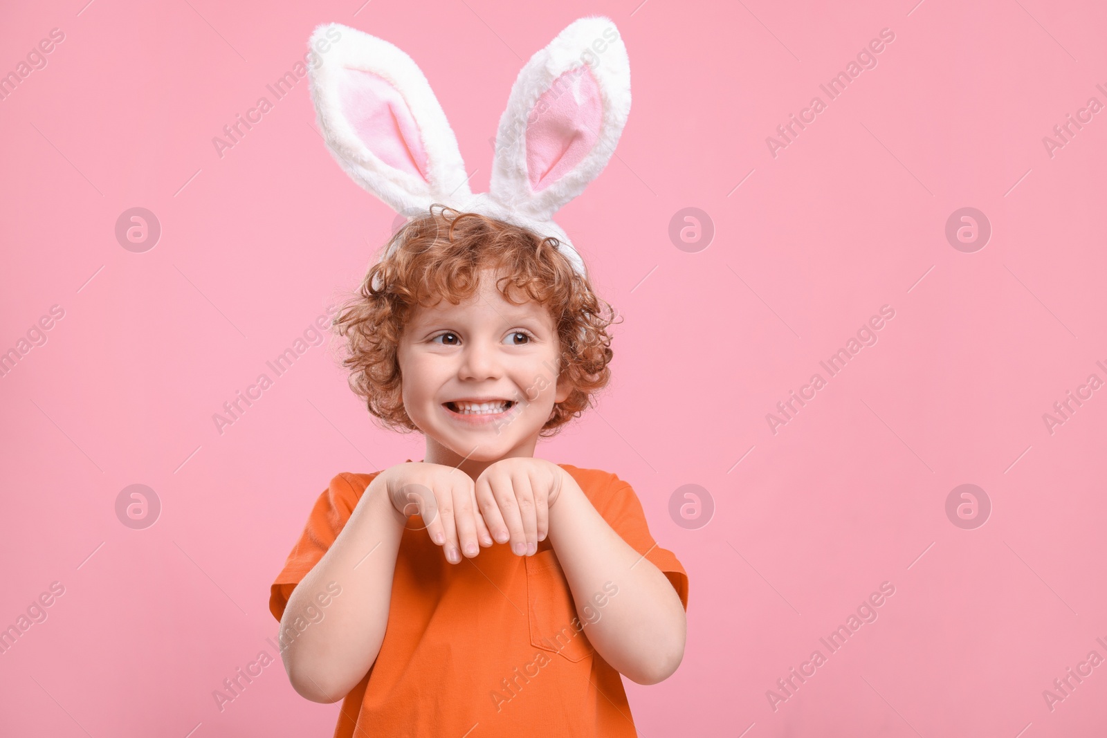 Photo of Happy boy wearing cute bunny ears headband on pink background, space for text. Easter celebration