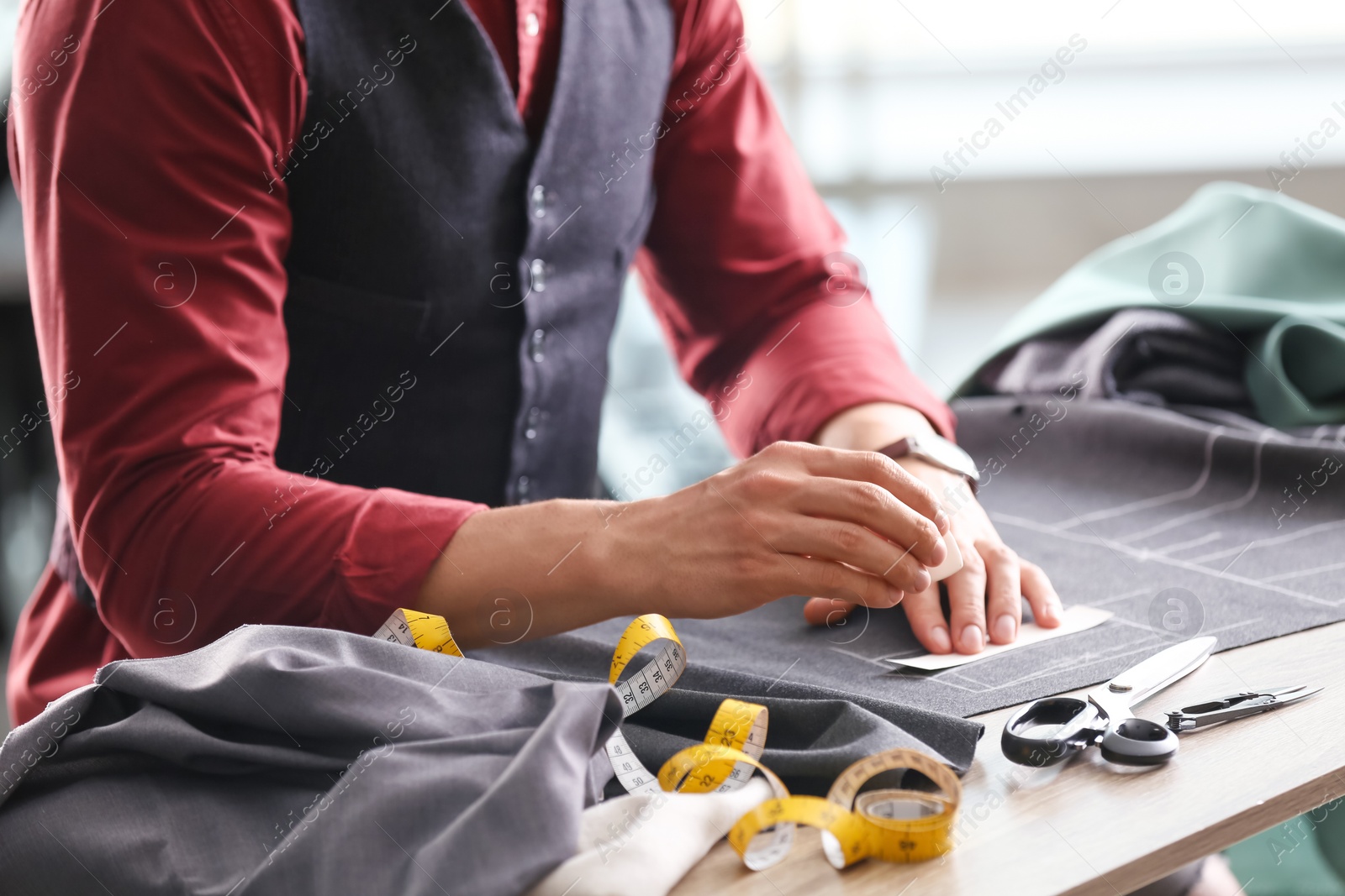 Photo of Tailor working at table in atelier, closeup