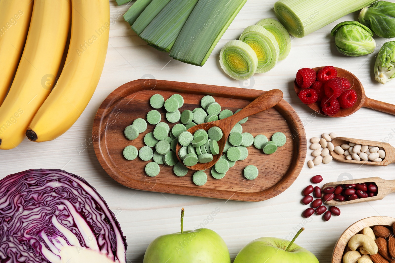 Photo of Many prebiotic pills and food on white wooden table, flat lay