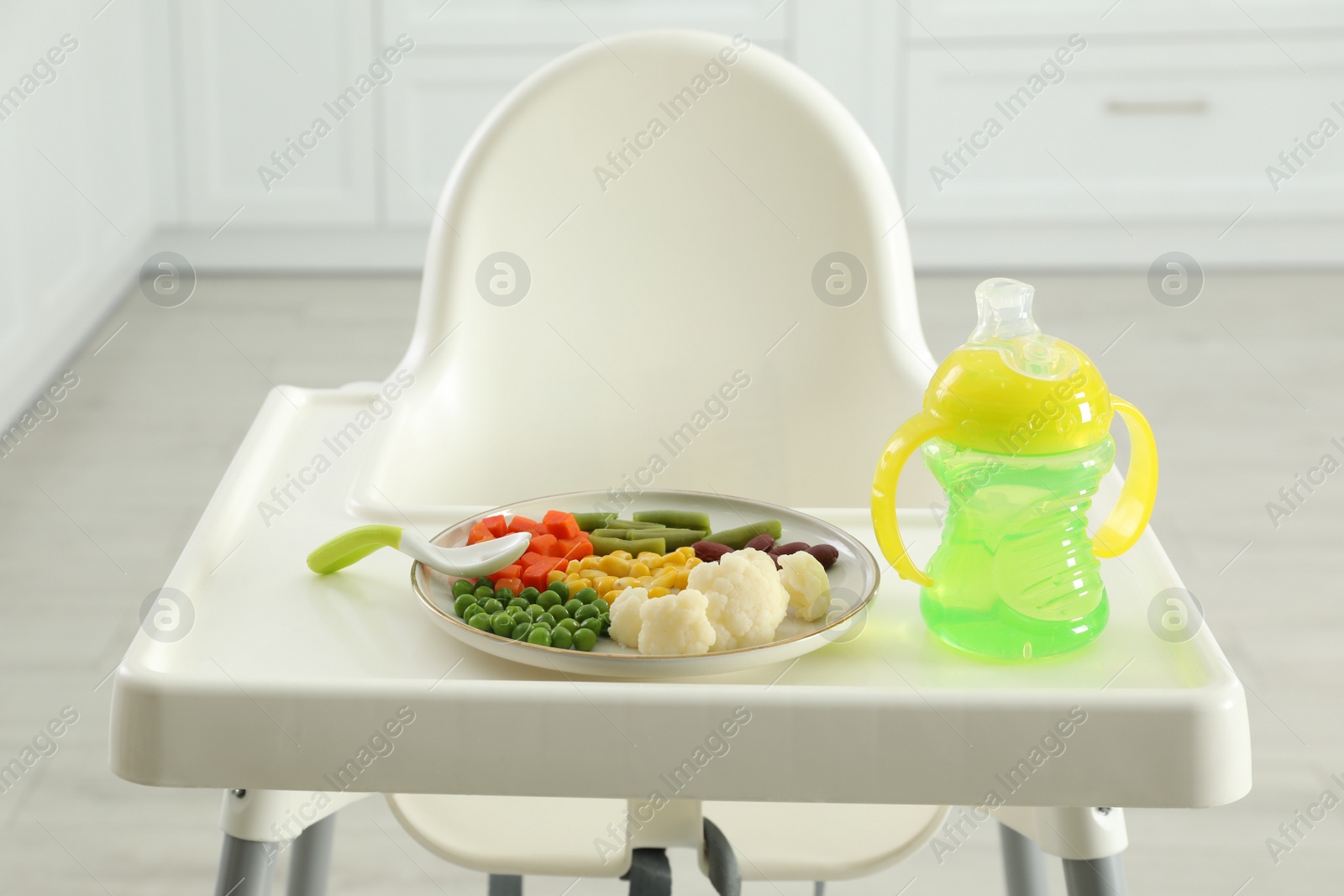 Photo of Baby high chair with healthy food and water indoors