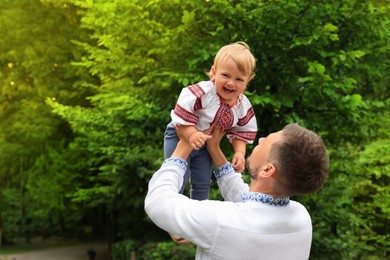 Photo of Man with his baby in national clothes outdoors