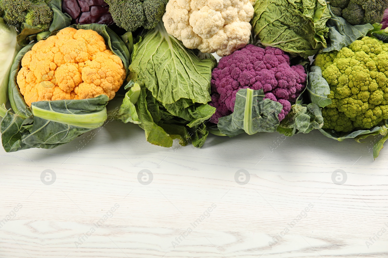 Photo of Different cabbages on wooden table, top view. Healthy food