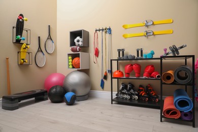 Many different sports equipment in room with beige walls