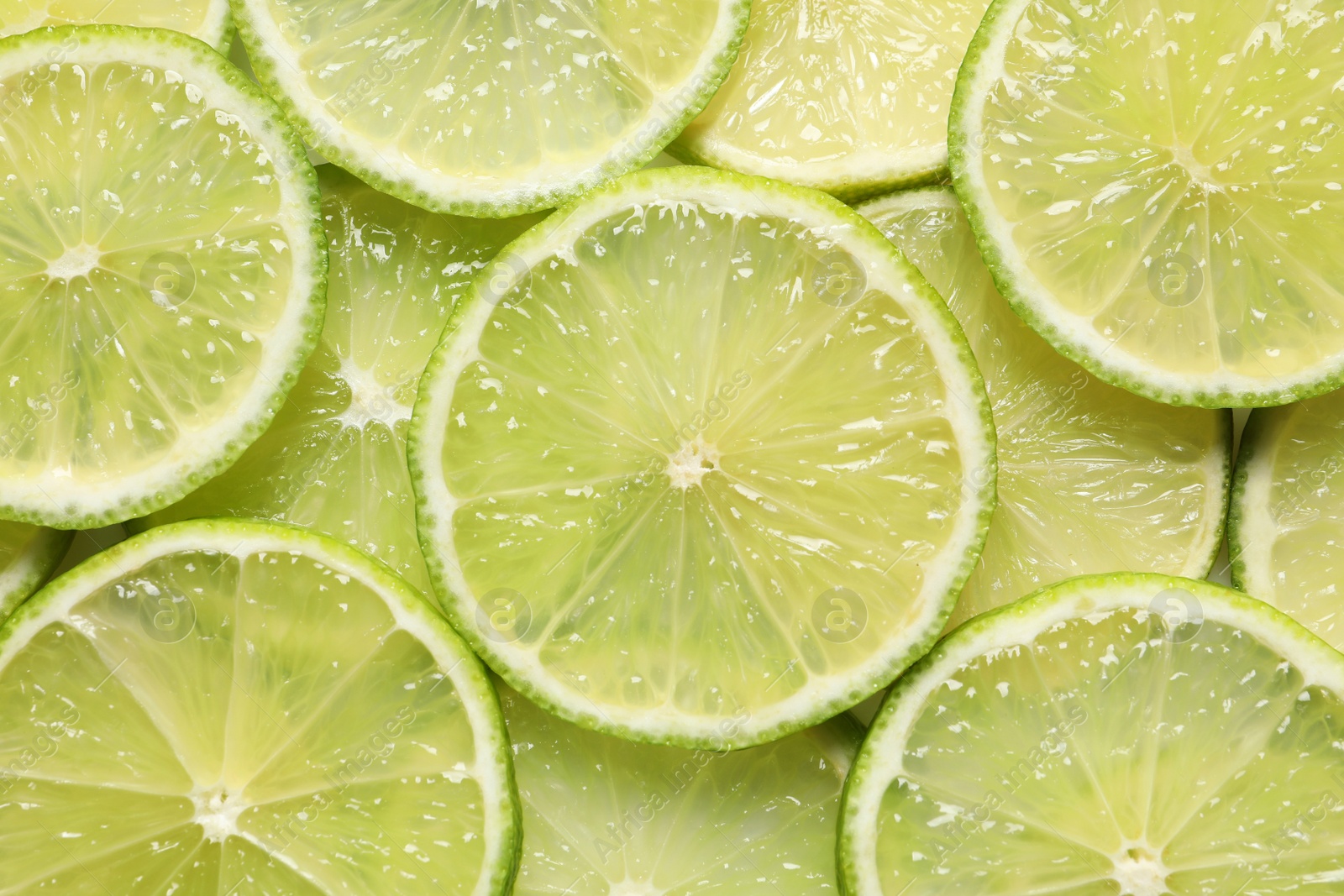 Photo of Juicy lime slices as background, top view. Citrus fruit