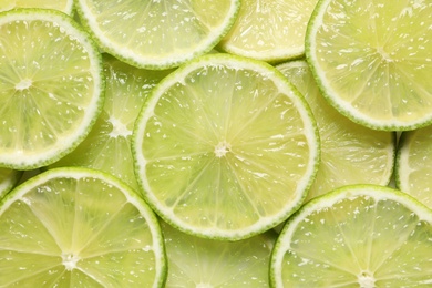 Juicy lime slices as background, top view. Citrus fruit