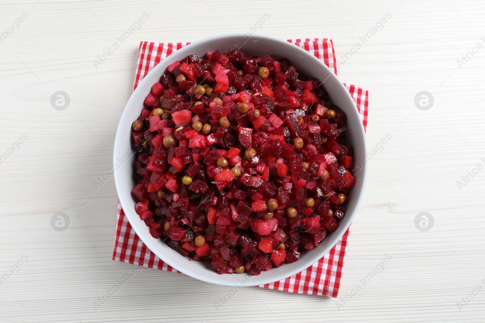 Photo of Bowl of delicious fresh vinaigrette salad on white wooden table, top view