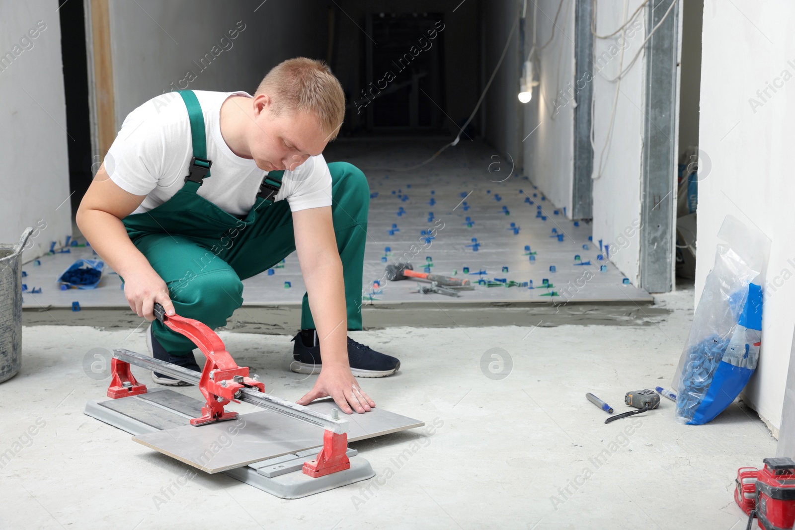 Photo of Worker using manual tile cutter in room