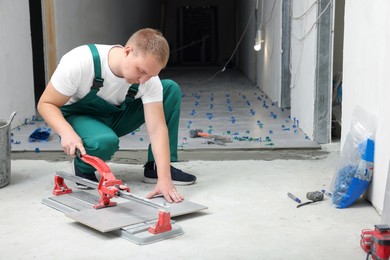 Worker using manual tile cutter in room