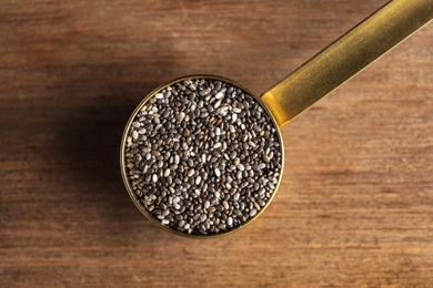 Photo of Scoop with chia seeds on wooden background, top view