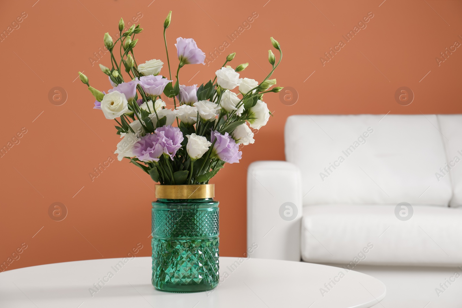 Photo of Bouquet of beautiful Eustoma flowers on table in living room. Space for text