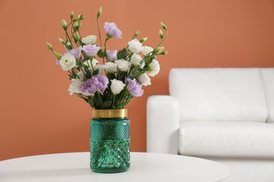 Photo of Bouquet of beautiful Eustoma flowers on table in living room. Space for text