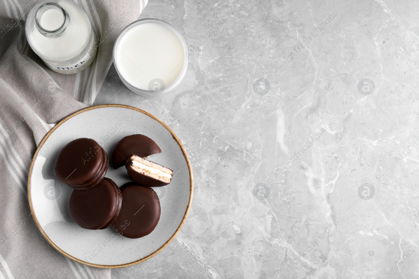 Photo of Tasty choco pies and milk on light grey marble table, flat lay. Space for text