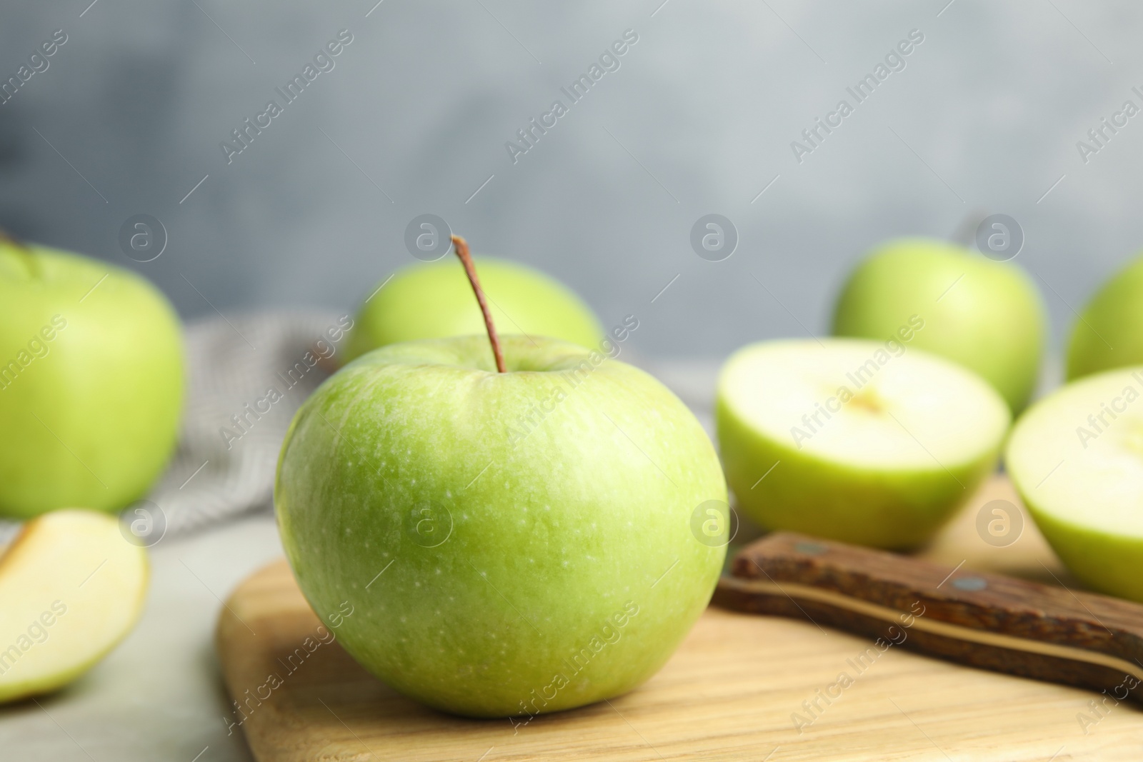 Photo of Fresh ripe green apple on wooden board against blue background, space for text