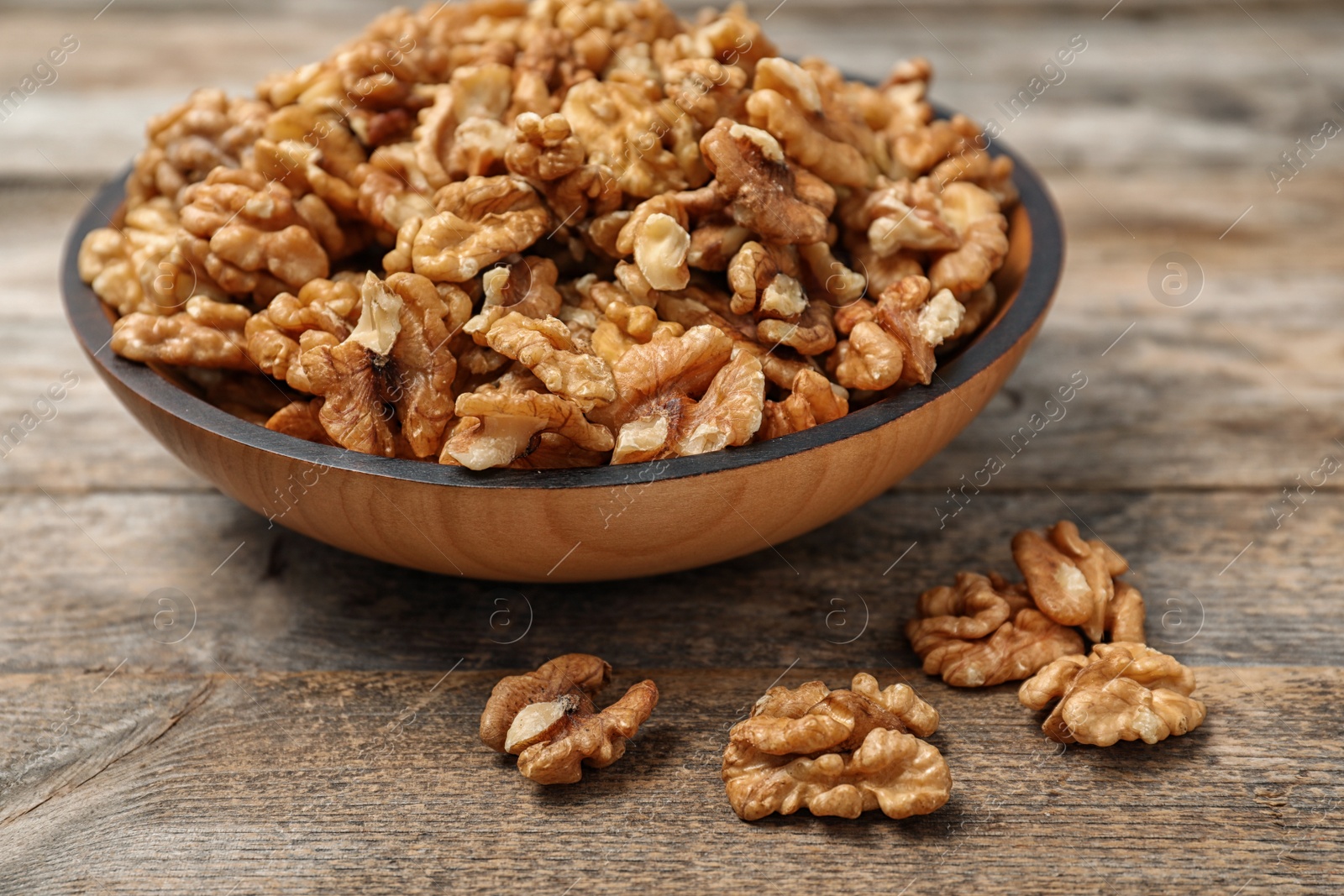 Photo of Plate with tasty walnuts on wooden table