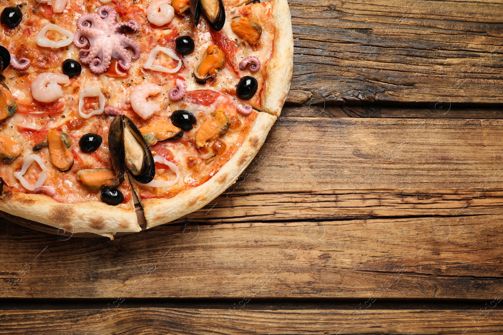 Photo of Delicious seafood pizza on wooden table, top view. Space for text