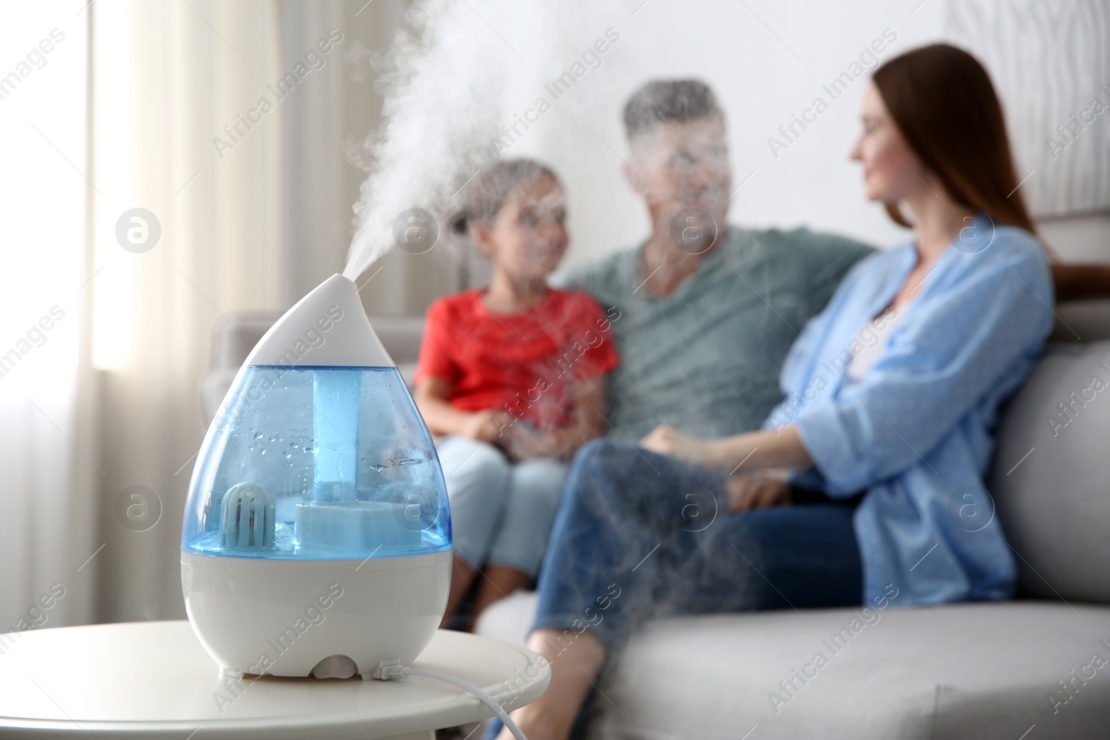 Photo of Modern air humidifier and blurred family on background