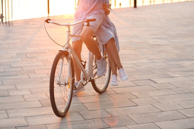 Young couple riding bicycle outdoors on summer day, closeup