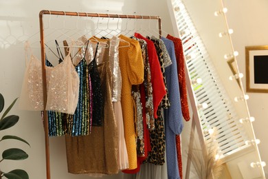 Photo of Rack with different stylish women's clothes and mirror indoors
